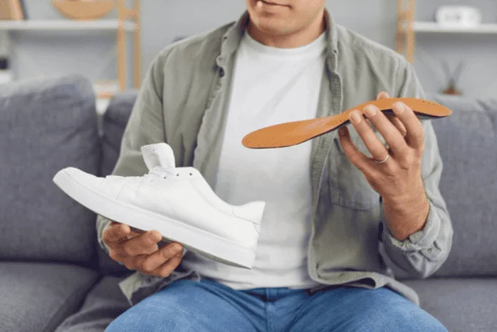 Man holding a white sneaker and an orthotic insole