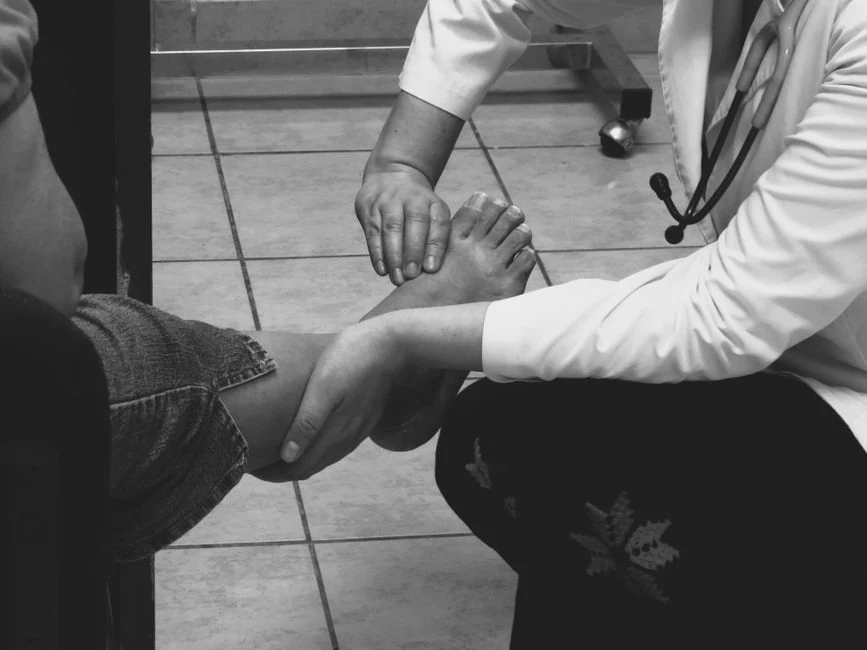 Clinician examines a patient's bare foot during an office visit.